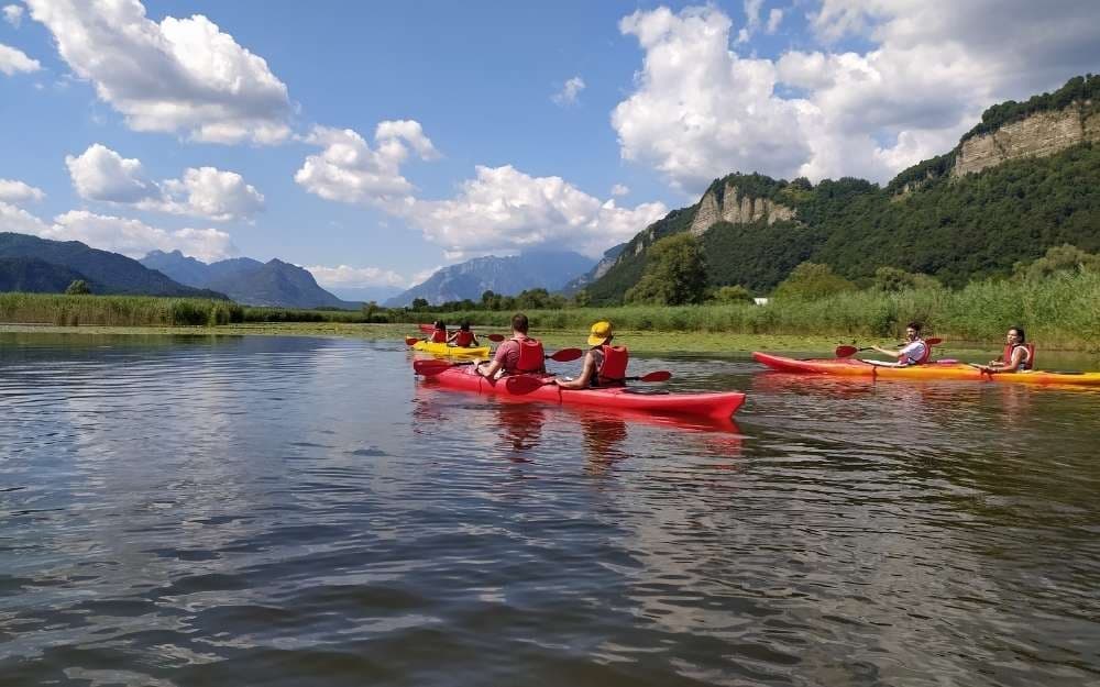 Group kayakers paddling on scenic mountain river under blue sky