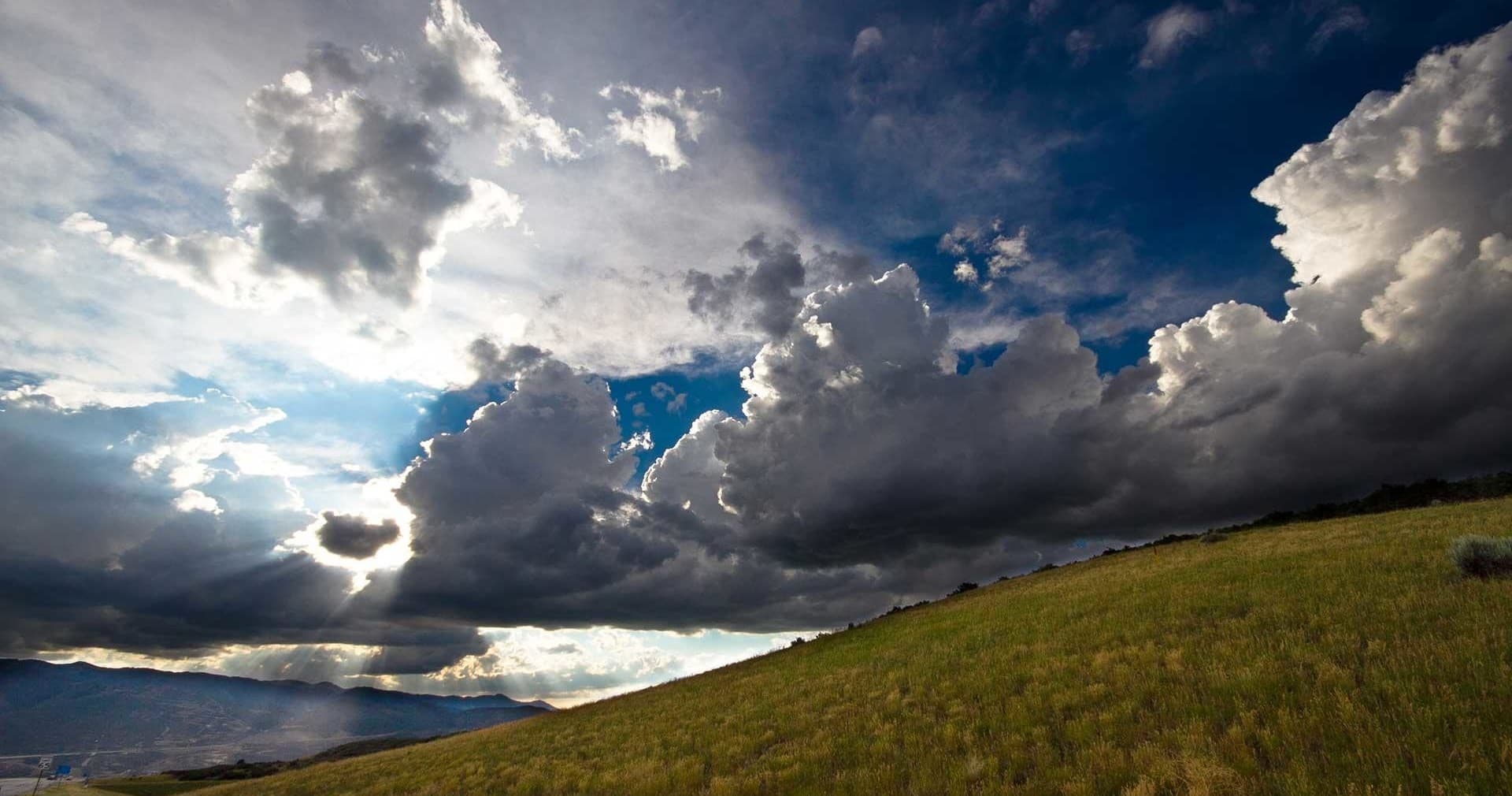 Dramatic storm clouds over grassy ridge, scenic hiking vista