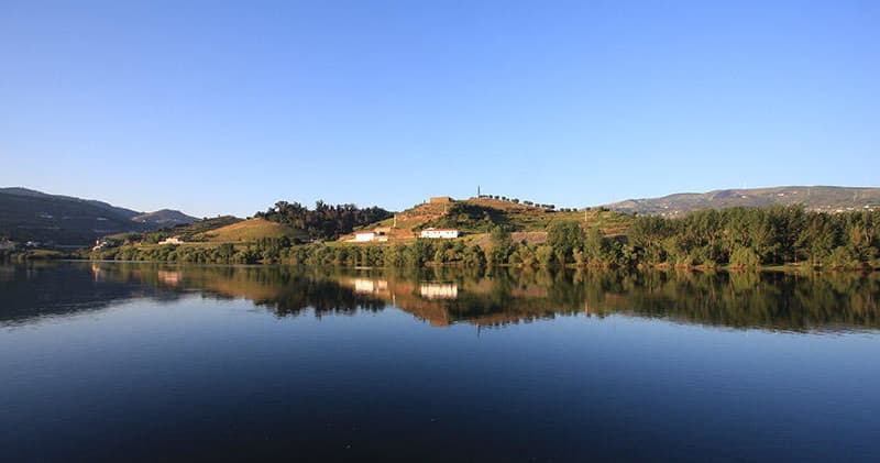 Calm Douro reservoir reflection with riverside manor view