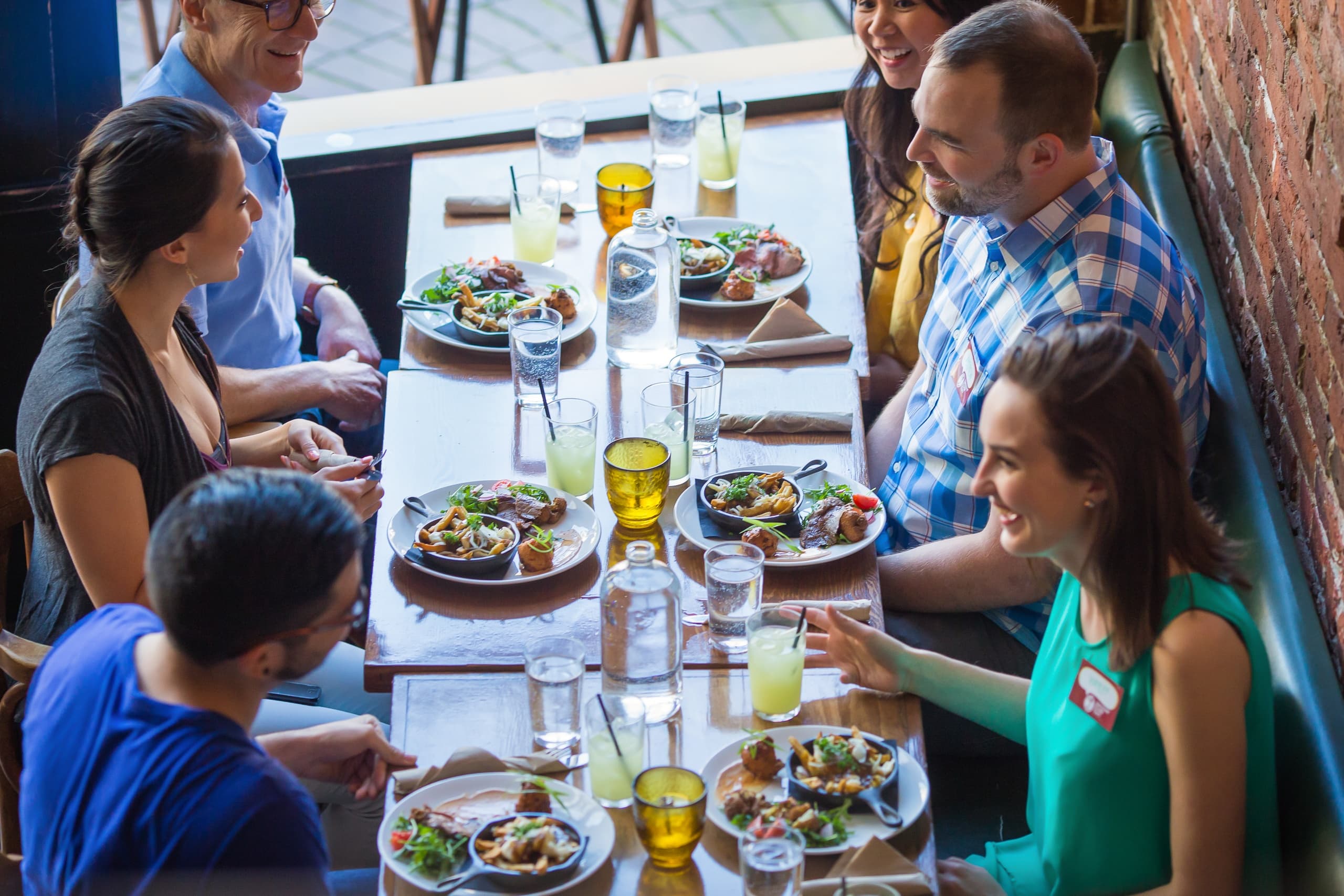 Friends enjoying communal lunch at bright urban restaurant table
