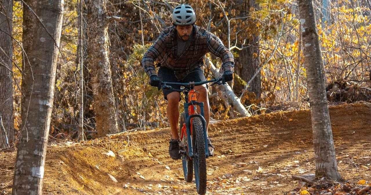 Mountain biker descending wooded trail through autumn foliage