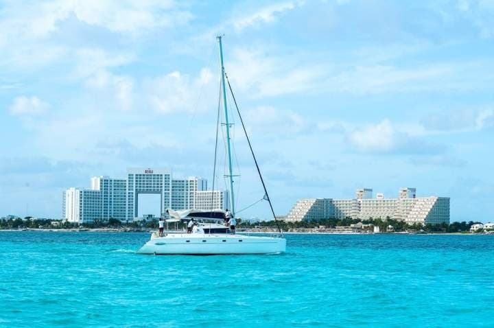 Sailboat cruising on clear turquoise ocean near coastline
