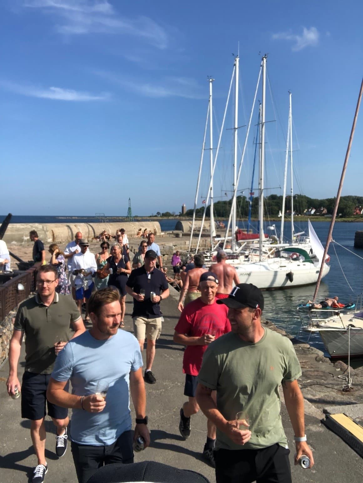 Participants walking along marina waterfront past sailboats