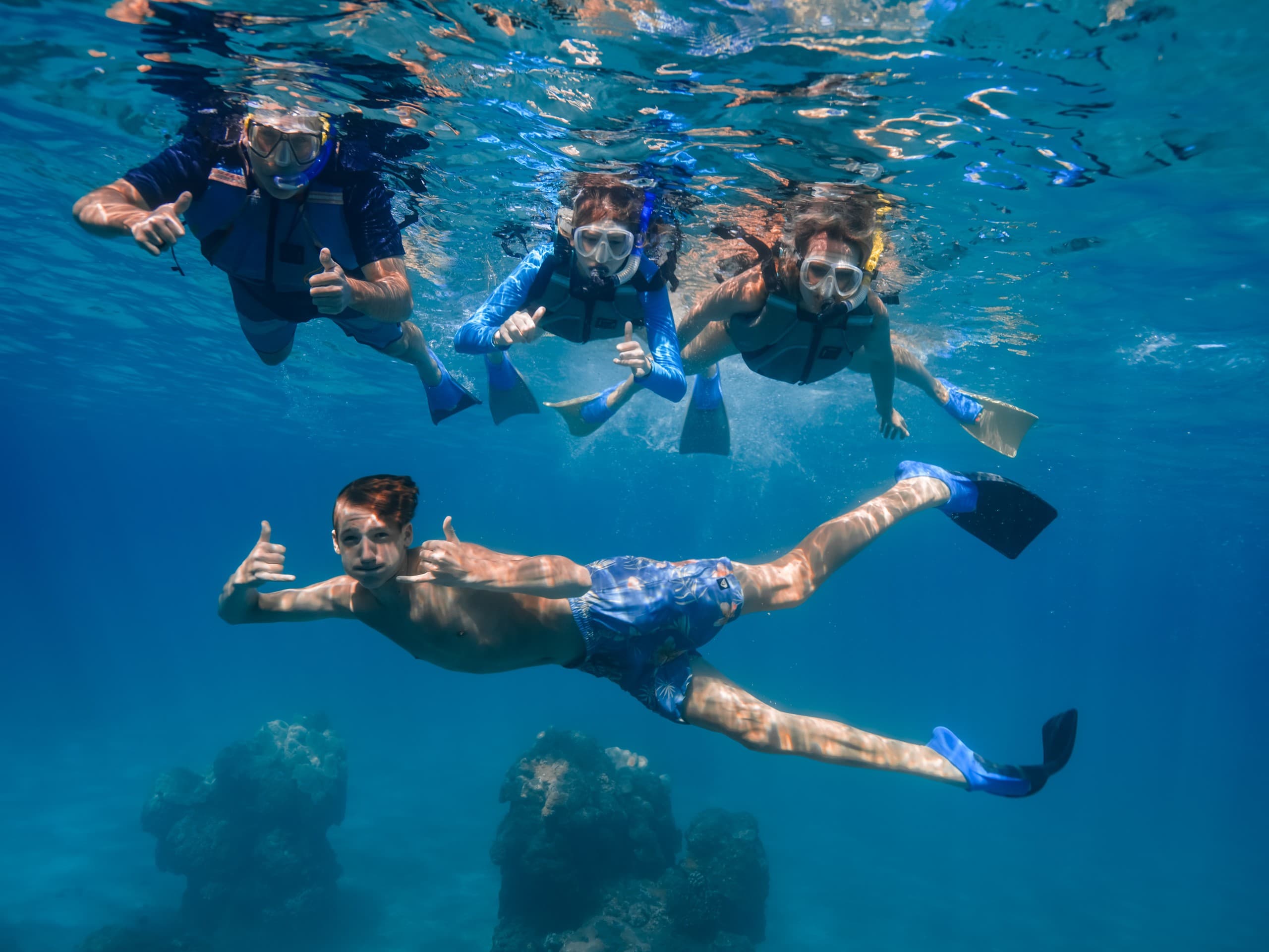 Group snorkeling over coral reef off Lanai, underwater action