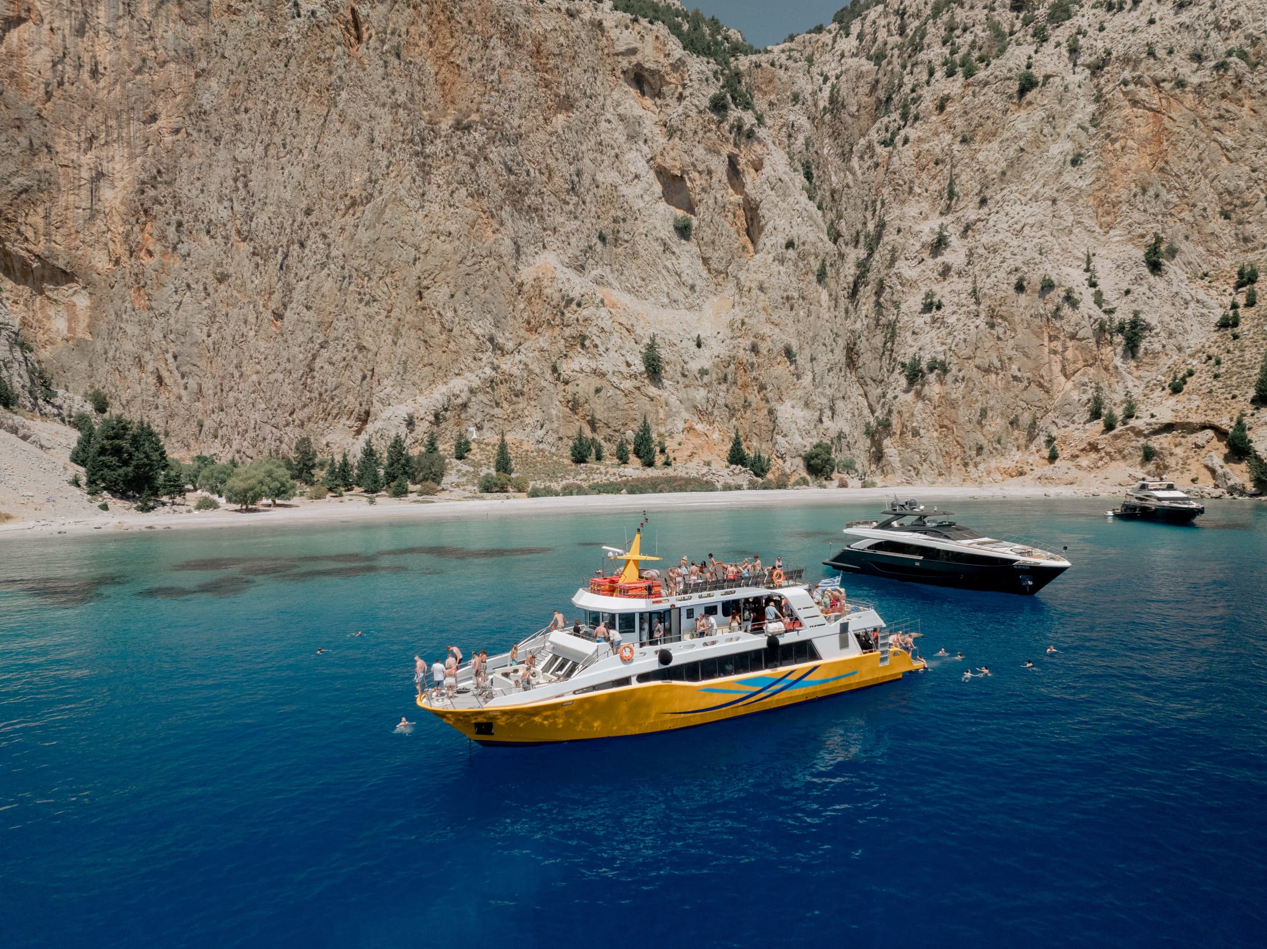Tour boat anchored near dramatic rocky cliffs and turquoise cove