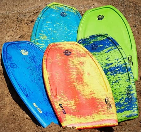 Colorful bodyboards resting on warm sandy beach at coastline