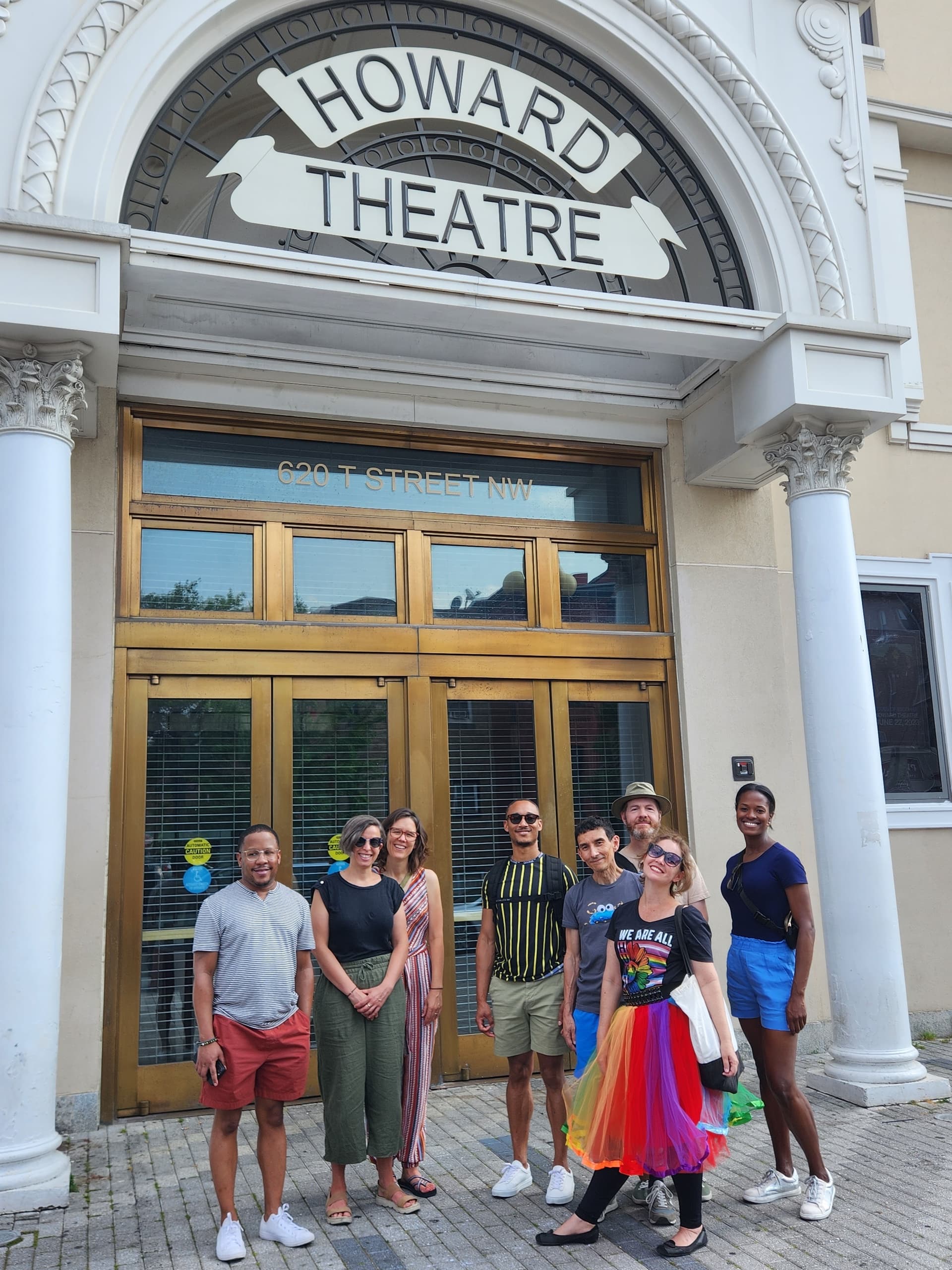 Tour group at historic theater entrance on city sidewalk