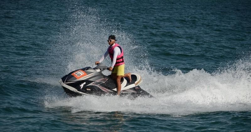 Solo rider on jet ski cutting through open ocean with spray