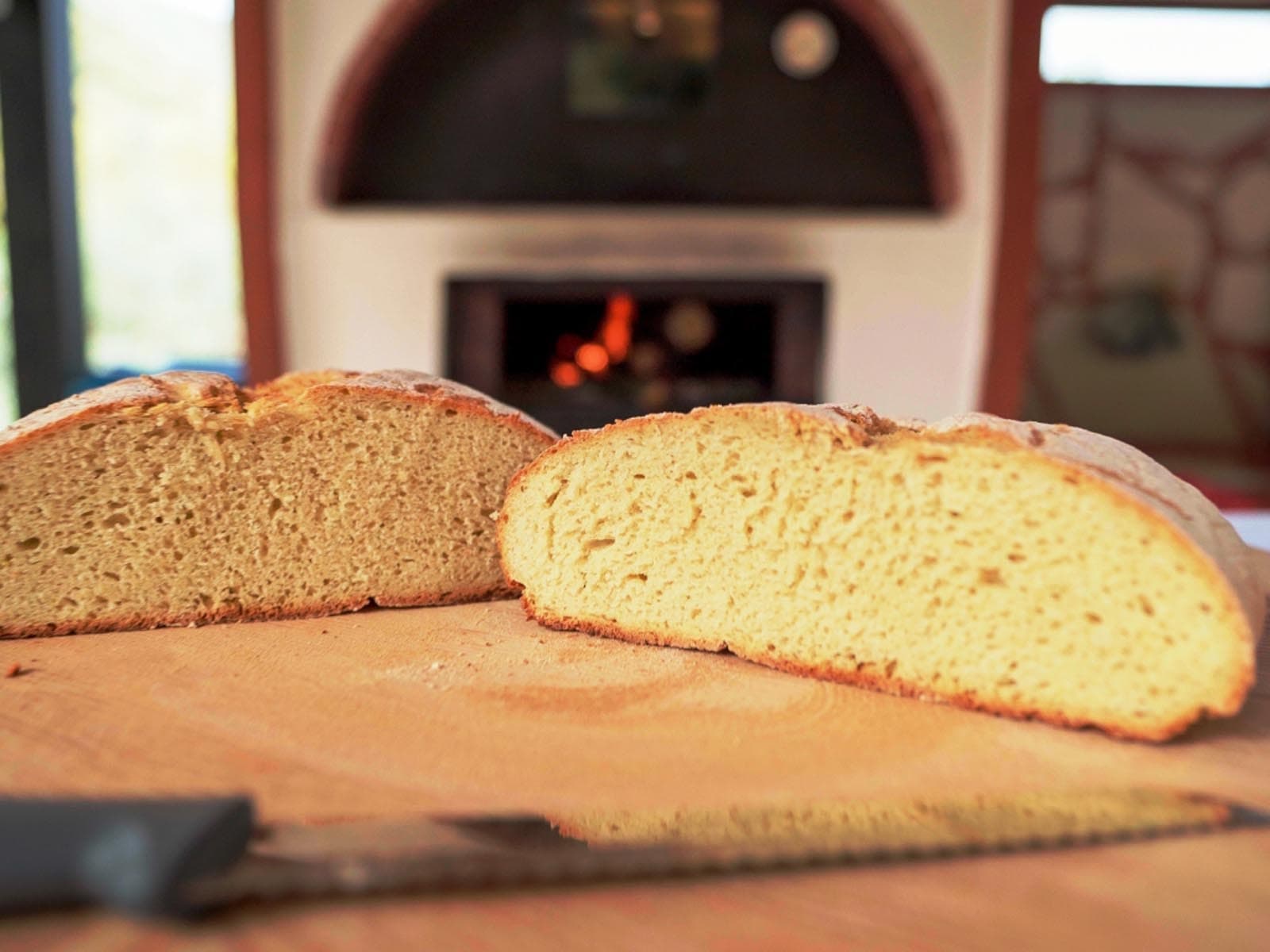 Freshly baked farmhouse bread sliced near wood-fired oven