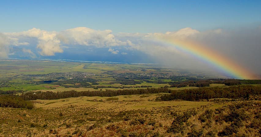 Wide countryside vista with vivid rainbow over fields