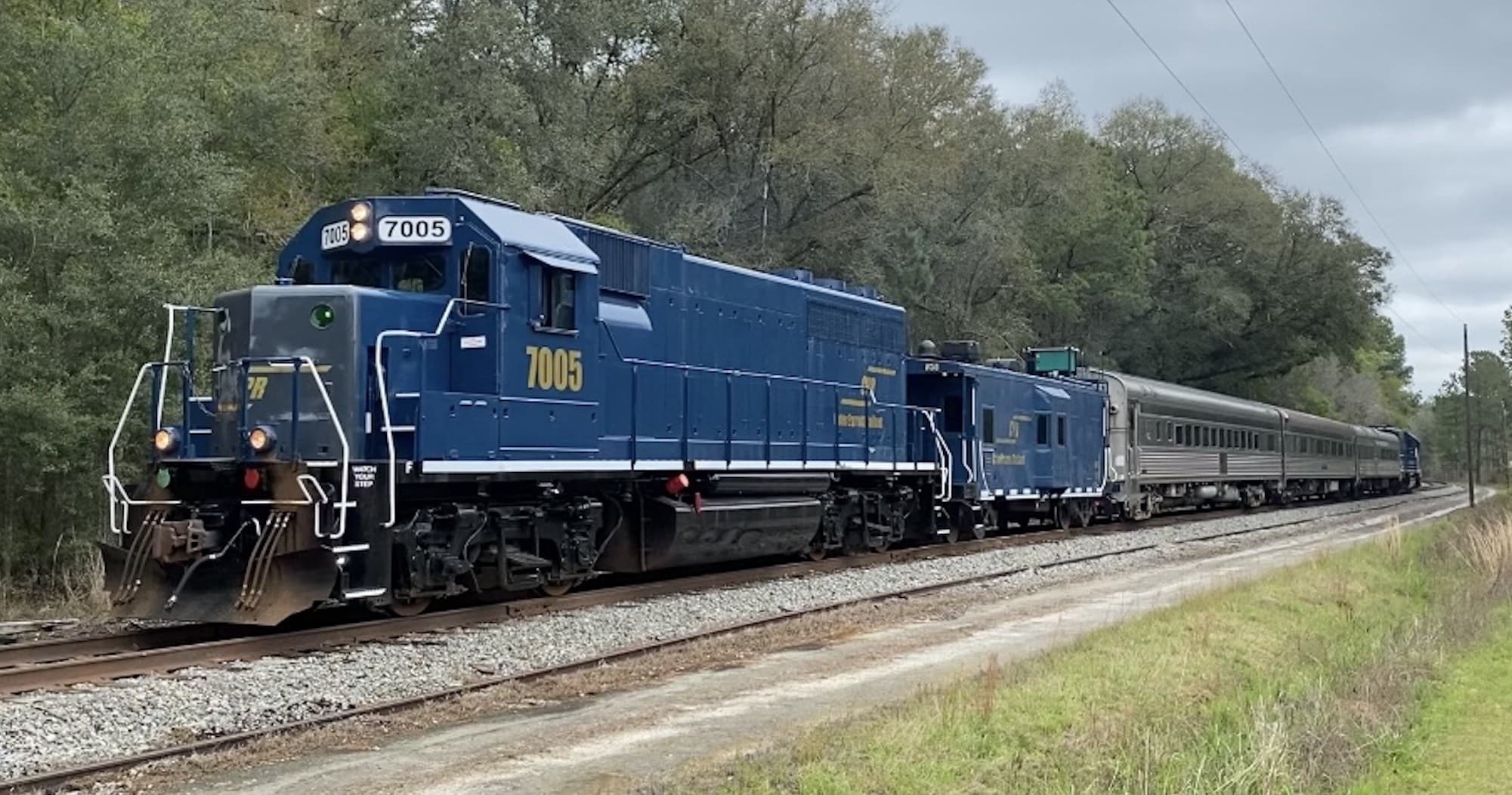 Diesel passenger train traveling through rural wooded landscape