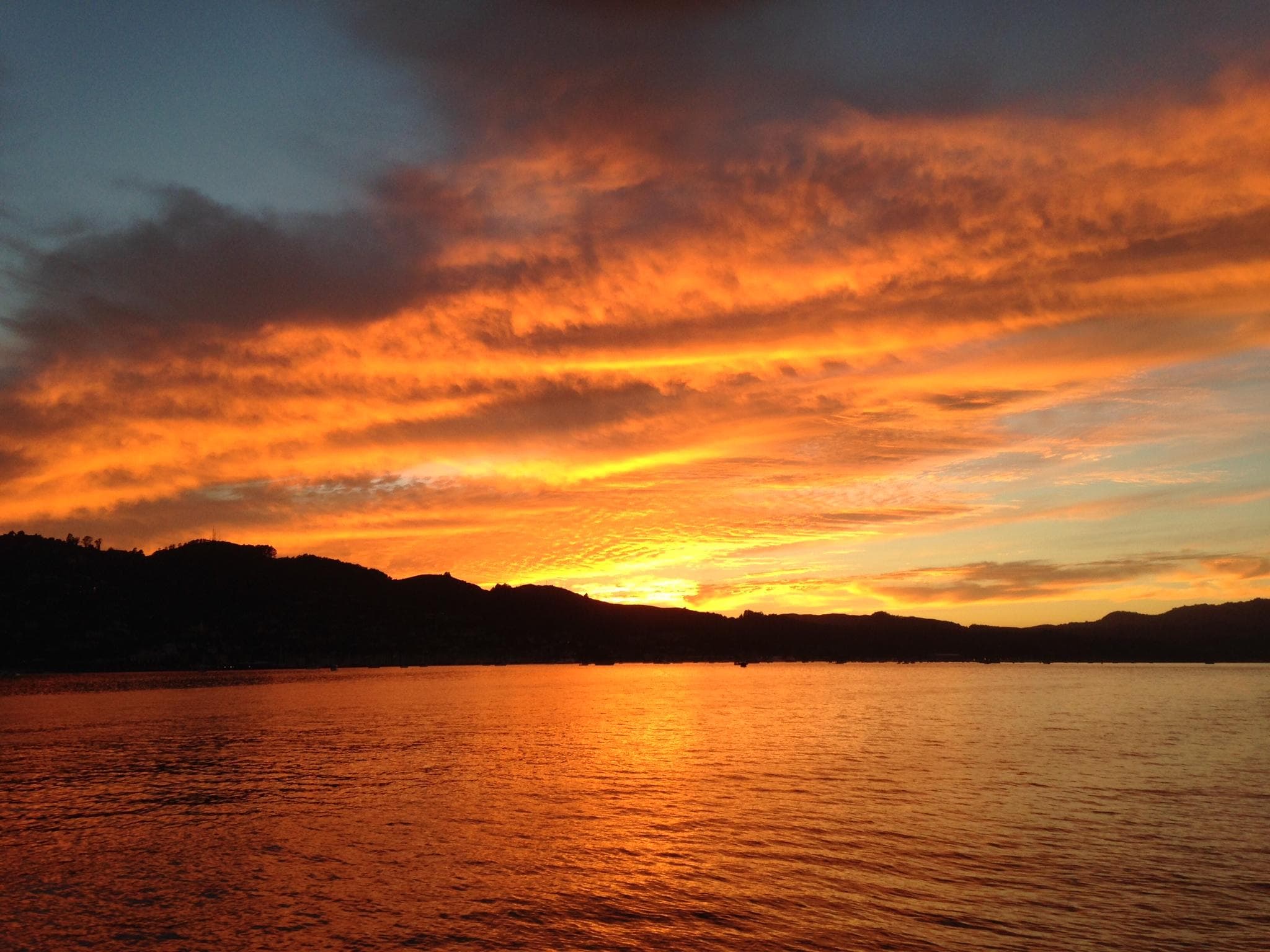 Dramatic orange sunset over bay with ferry silhouetted