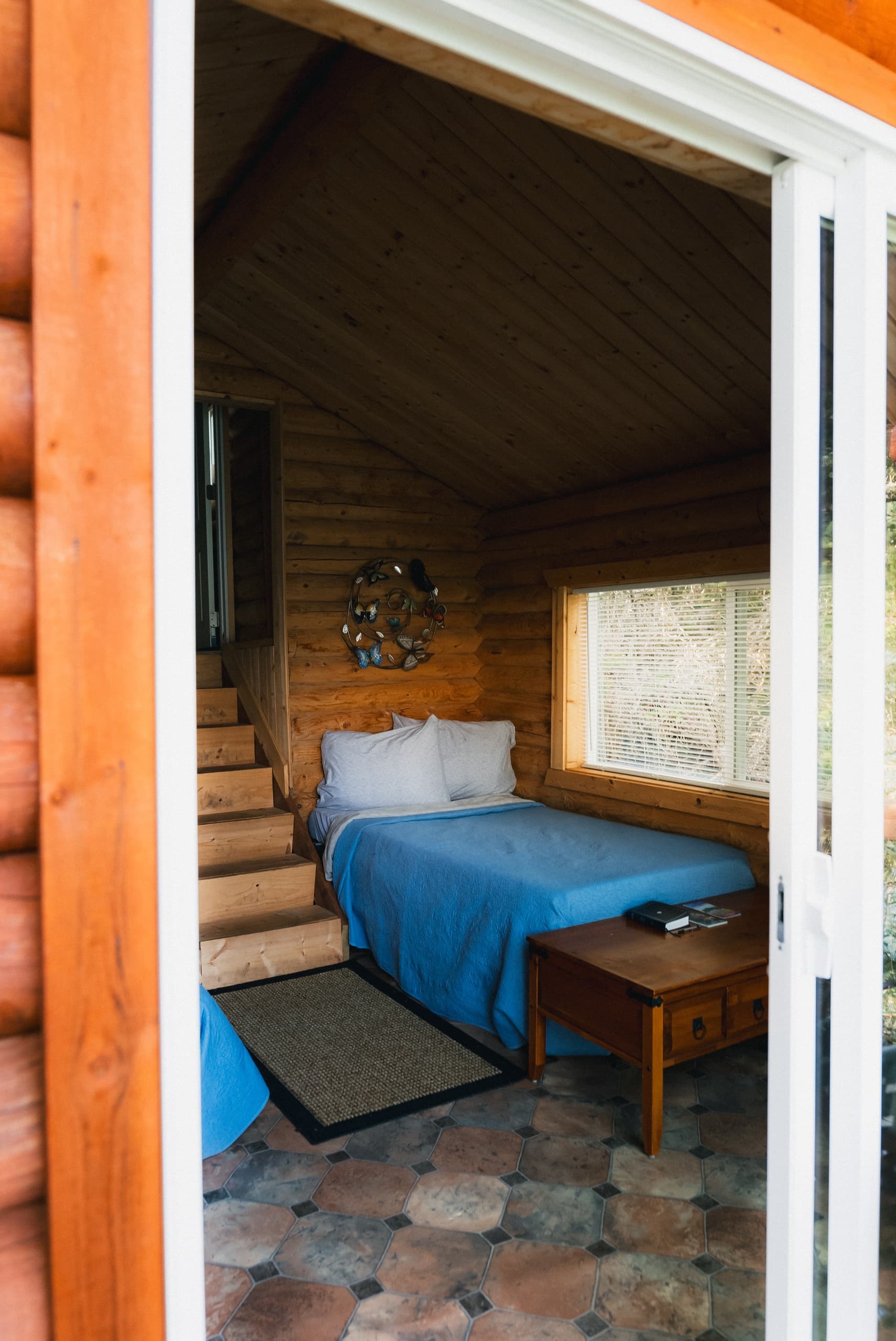 Small cabin loft bedroom seen through open doorway with rustic decor