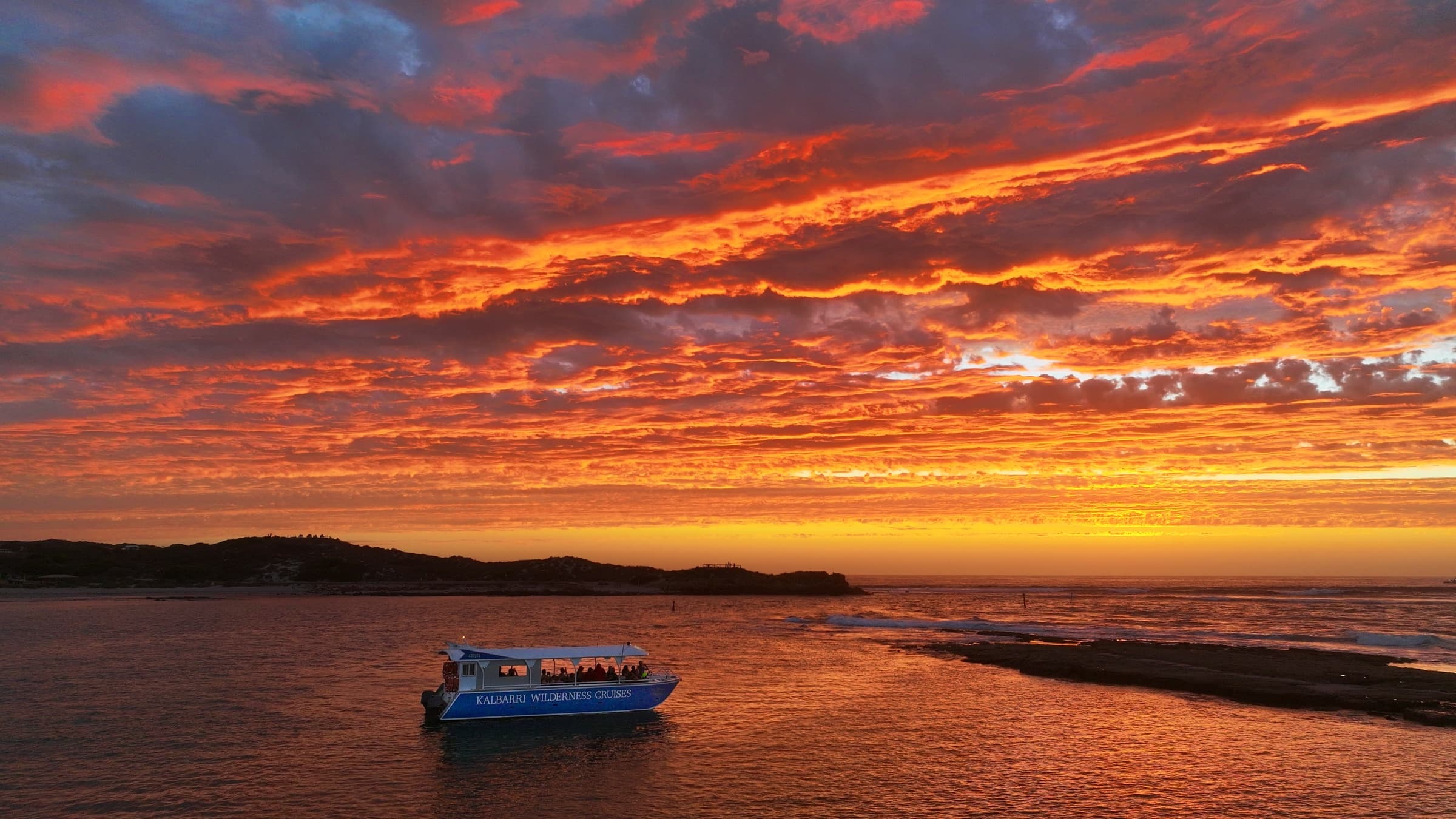 Cruise boat at fiery sunset over coastal waters, scenic cruise