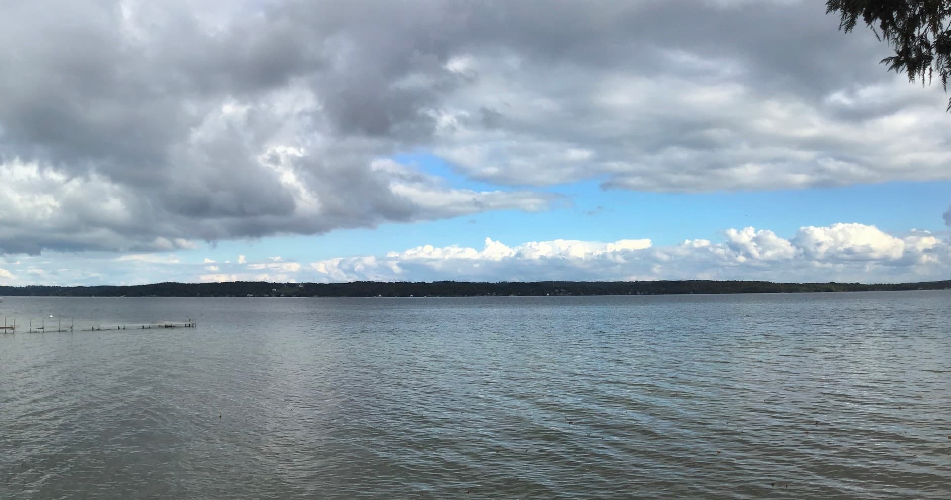 Wide lake panorama under dramatic cloudy sky, peaceful
