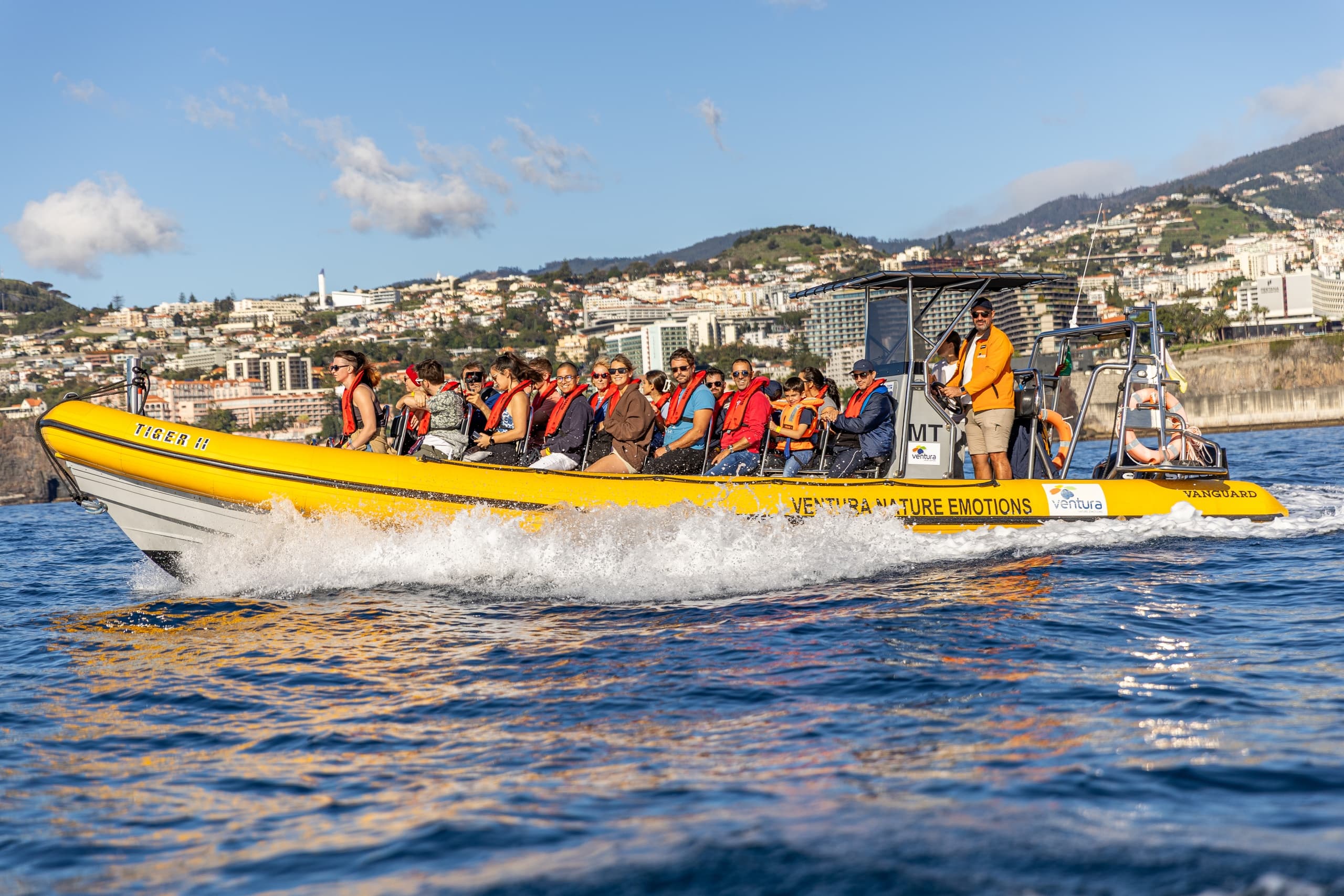 High-speed RIB boat tour with passengers off coastal city shore