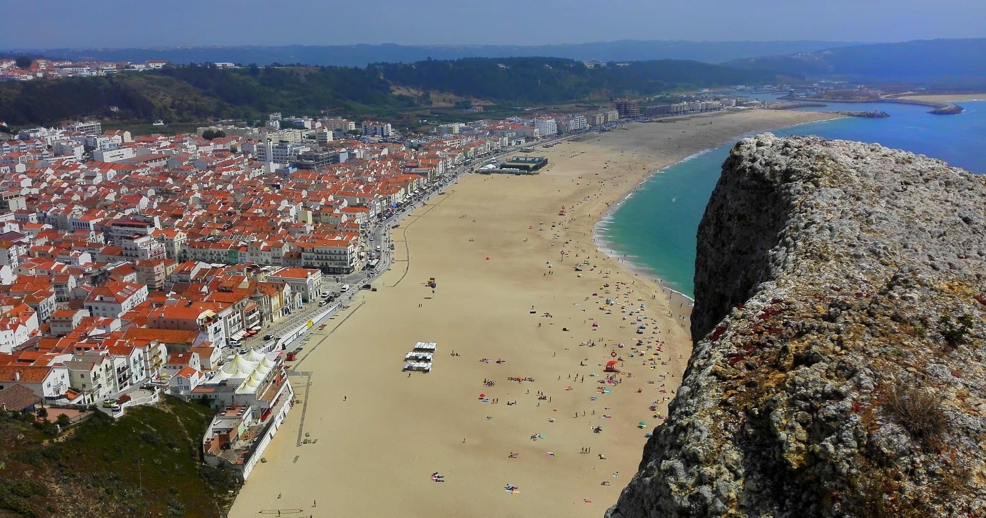 Wide Nazaré beach panorama with cliffs and sandy shore