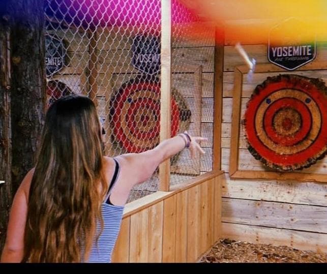 Woman throwing axe at target in Yosemite indoor axe throwing lane