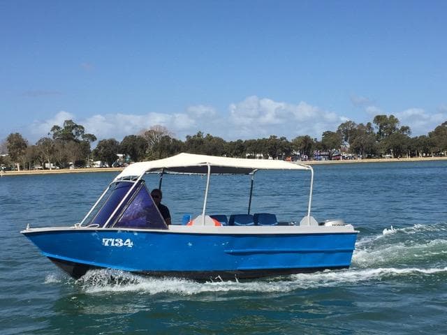 Small blue launch speeding across Mandurah coastal waters