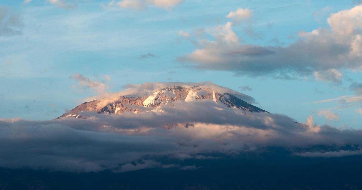 Sunlit mountain peak rising above clouds, alpine trekking vista