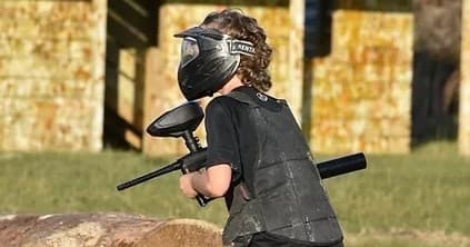 Youth paintball player taking cover on outdoor field