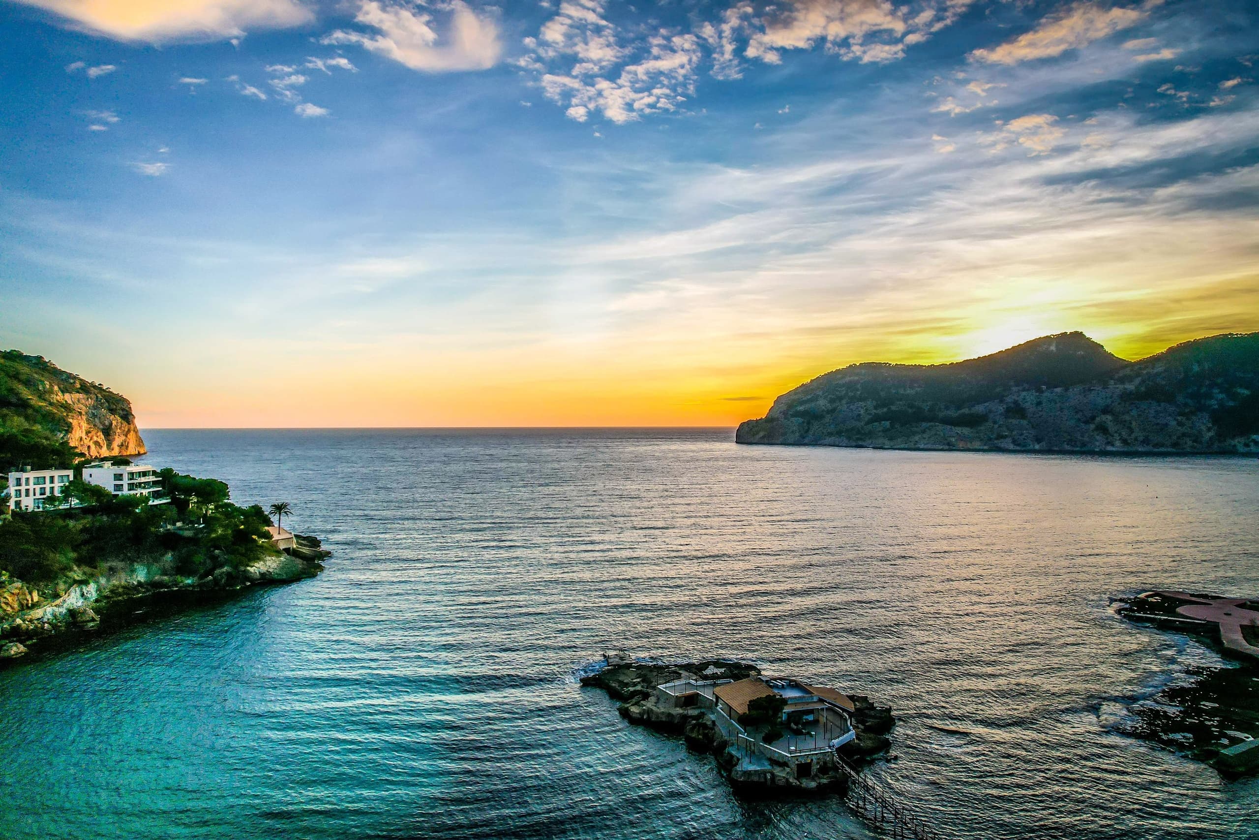 Scenic coastal sunset over Mediterranean bay with rocky cliffs