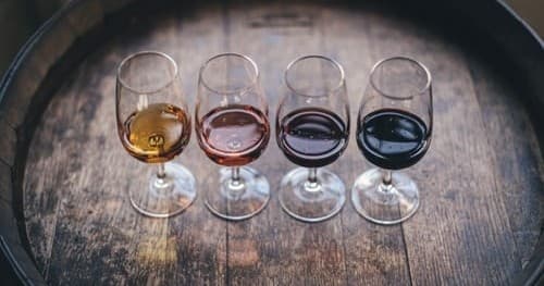Flight of tasting wines arranged on oak barrel at winery