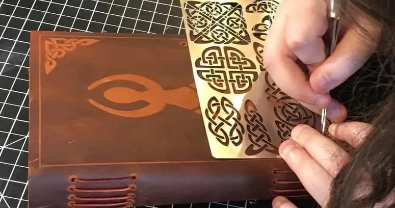 Artisan leatherworker tooling journal cover in craft studio