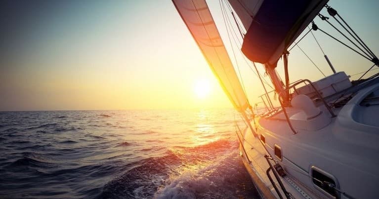 Sailboat cruising at sunset on open ocean, scenic sailing adventure