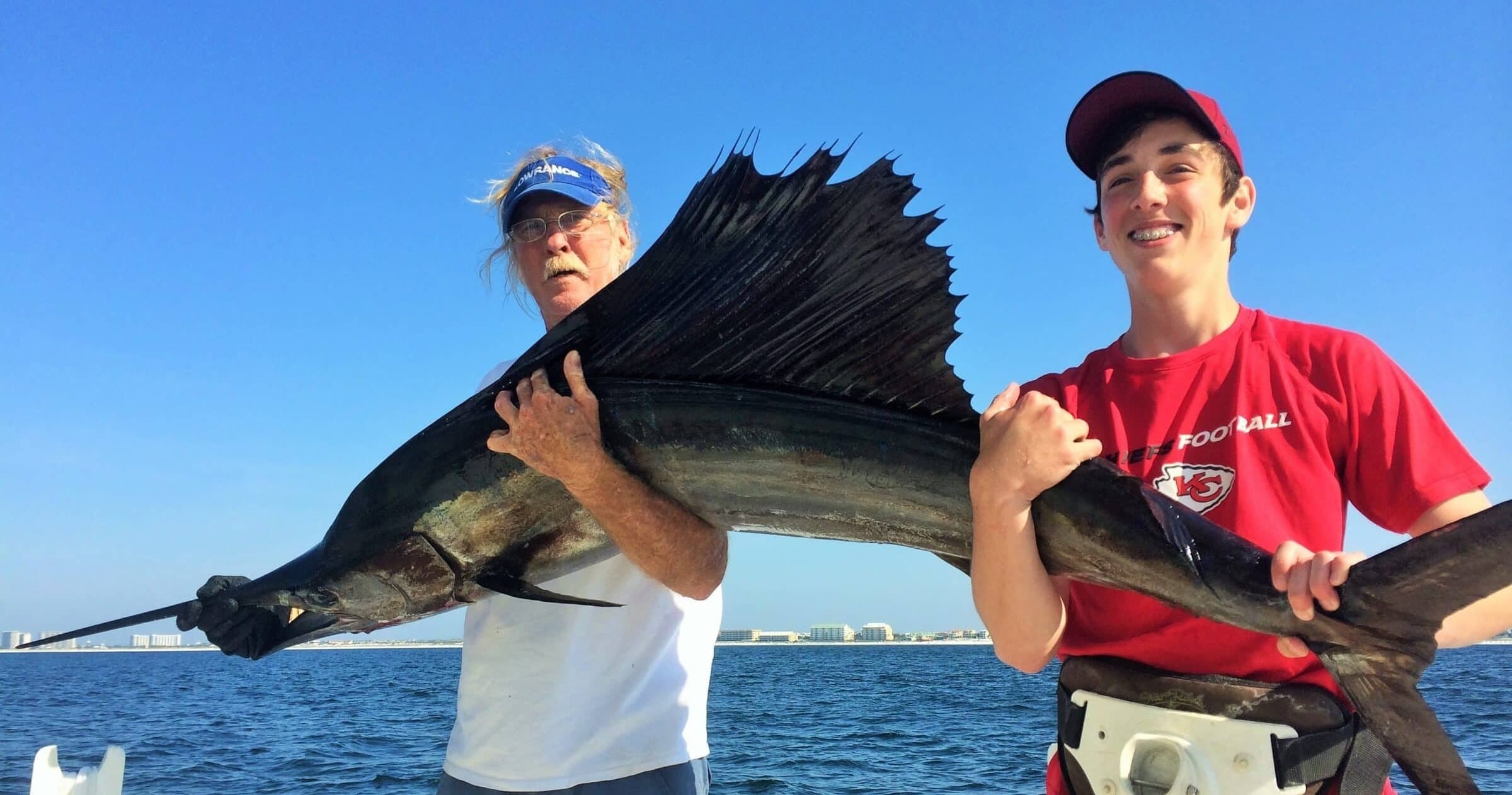 Anglers holding sailfish on offshore charter boat during sportfishing