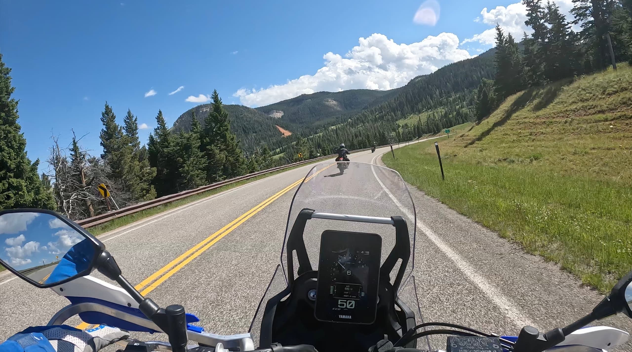 Motorcycle cockpit riding scenic mountain highway through pine forests