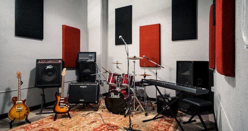 Music rehearsal corner with drum set, bass guitars, amps