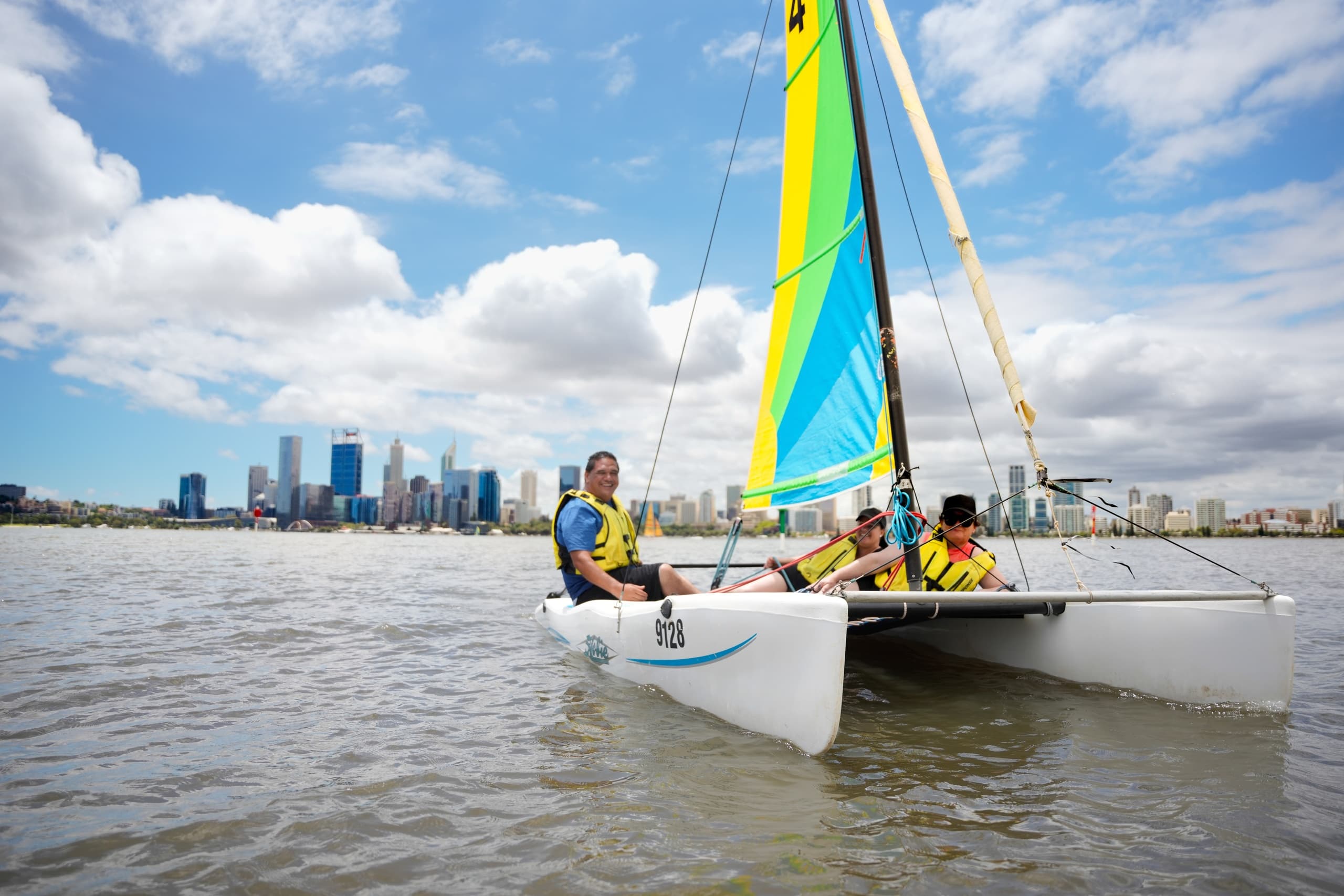 Catamaran sailing near city skyline on sunny harbor