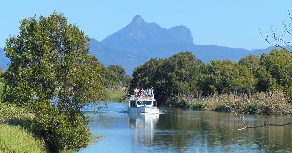 Boat cruising river beneath Mount Warning scenic mountain view