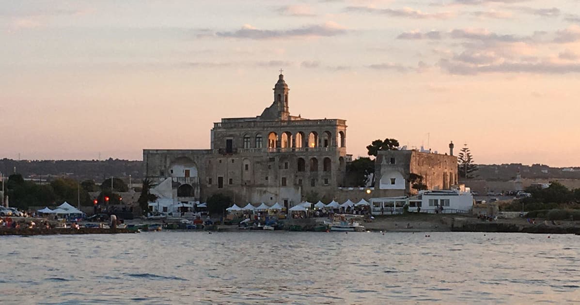 Historic coastal fortress at sunset seen from a calm sea tour