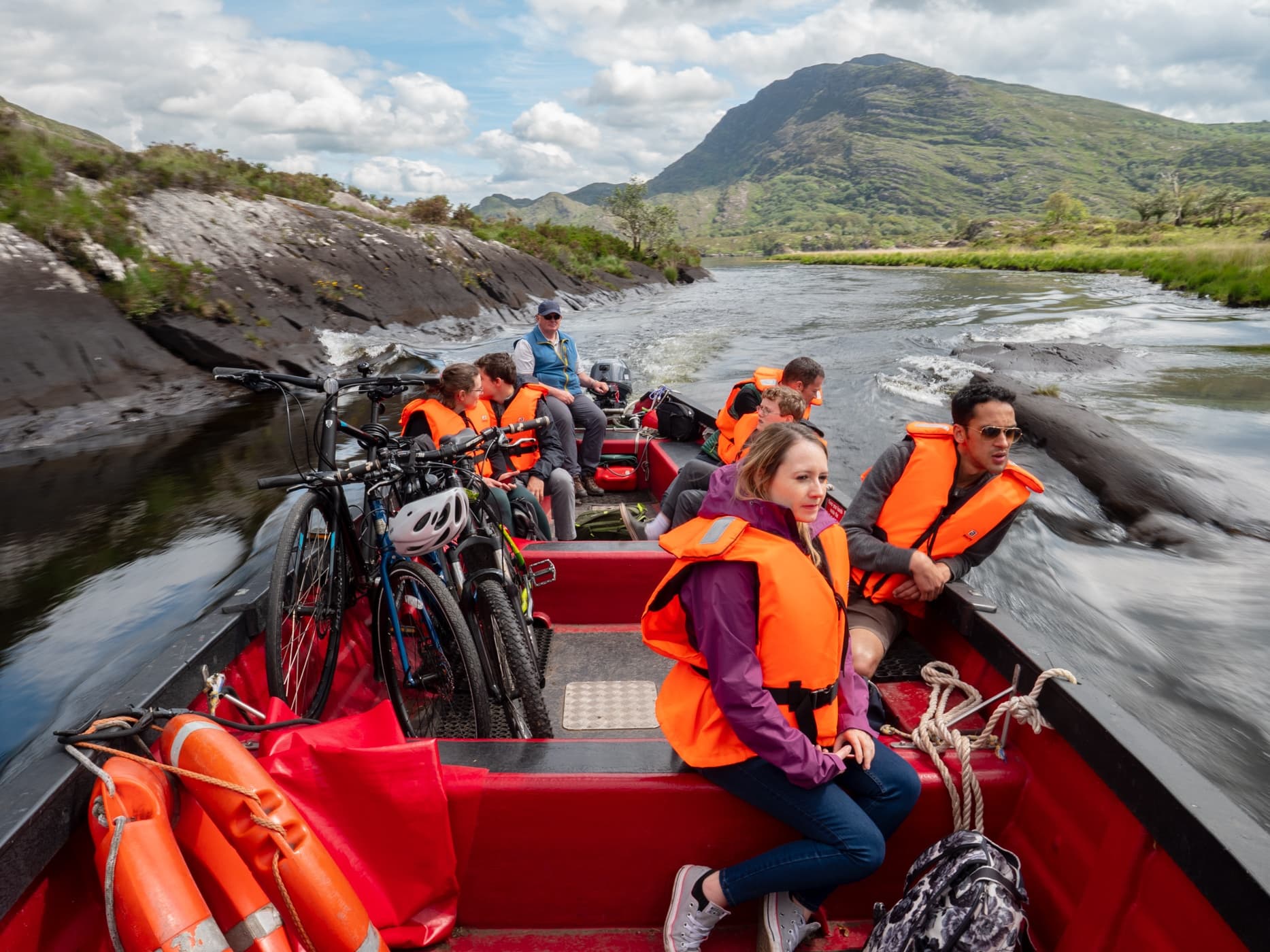 Open boat with cyclists and passengers navigating scenic river