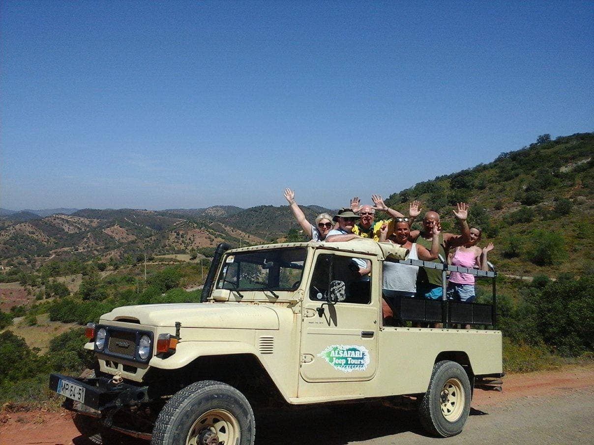 Open-top safari jeep driving through rugged countryside, wildlife tour