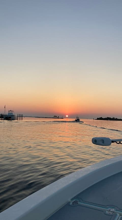 Small boat bow at sunrise on tranquil coastal waters, harbor approach