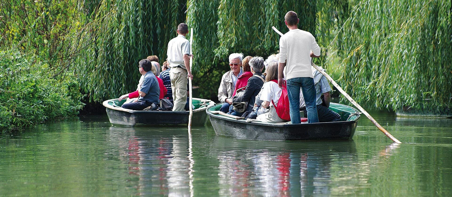 Guided punt boat with tourists on tree-lined river tour