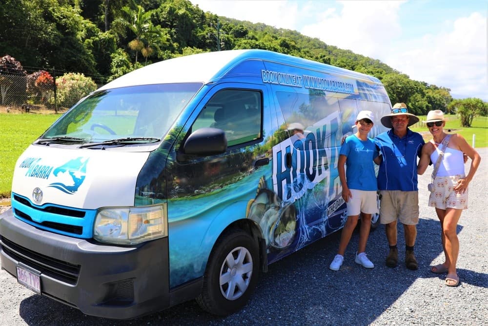 Branded tour van parked near lush coastal landscape with guides posing