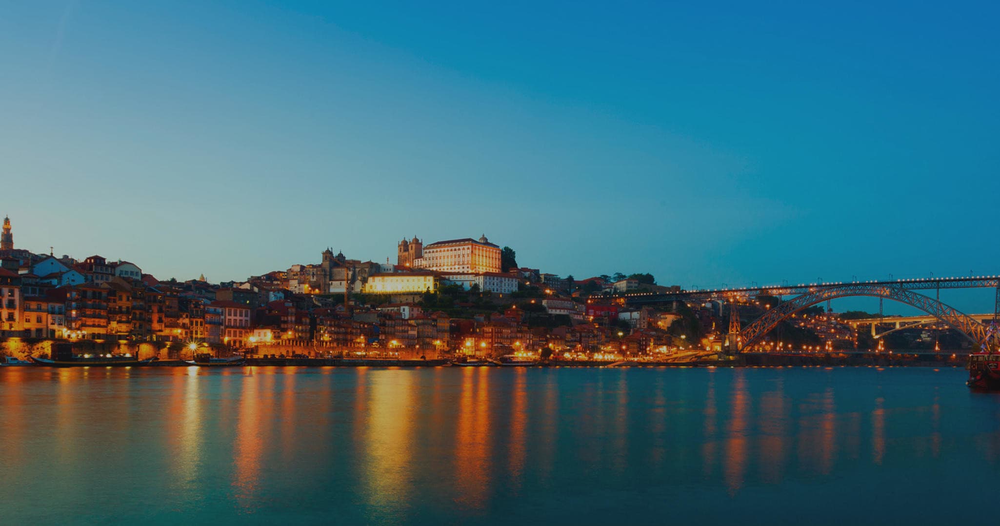Nighttime riverside cityscape with illuminated bridge and waterfront