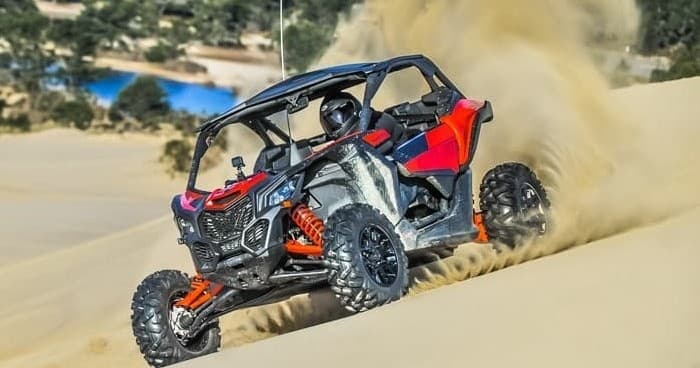 Off-road UTV throwing sand on coastal dunes for adrenaline ride