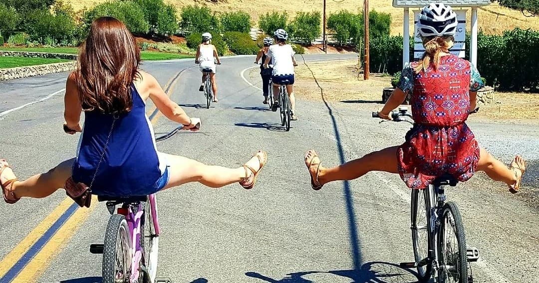 Friends cycling on country road, playful legs-out bike ride