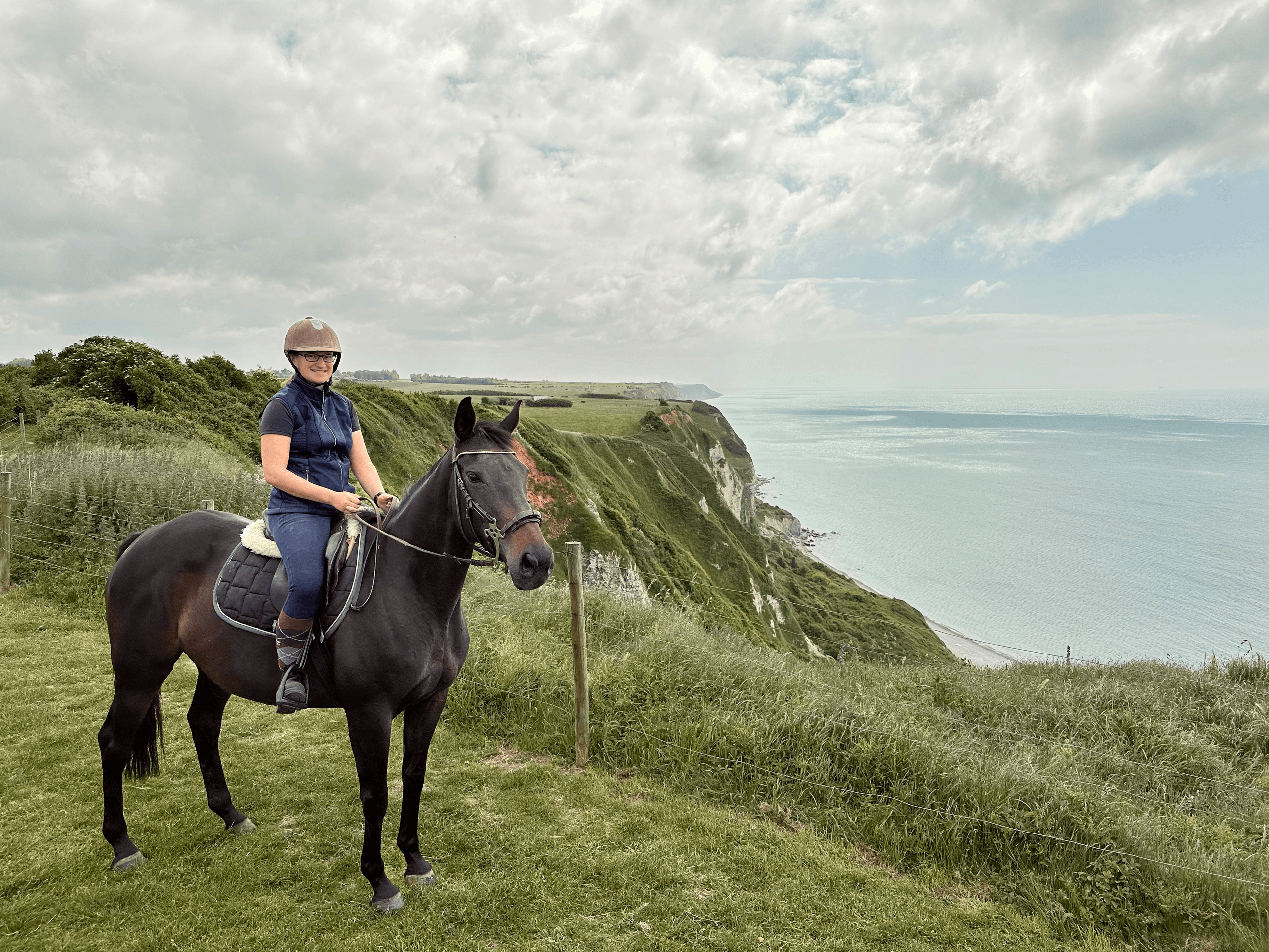 Rider on horseback posed beside dramatic sea cliff overlooking ocean
