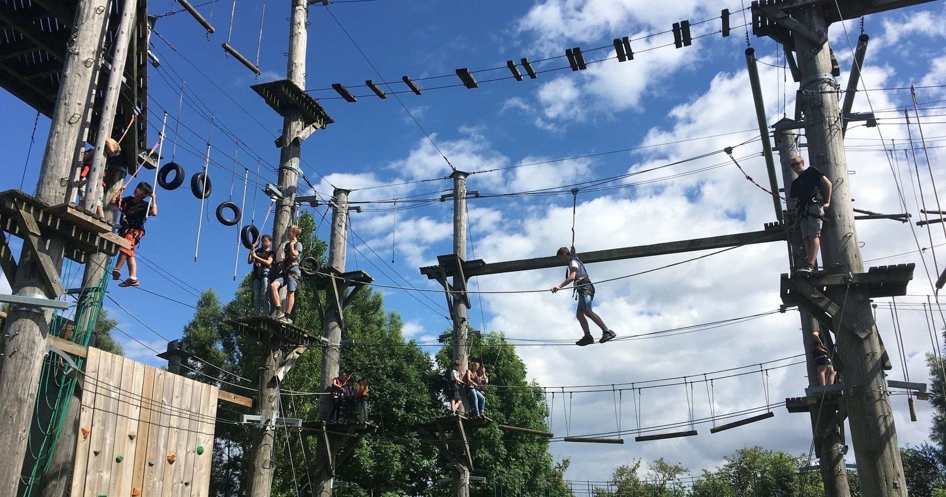 People navigating elevated rope obstacles on outdoor course