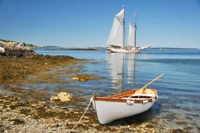 Small sailboat and tender ashore on rocky coast, calm sea