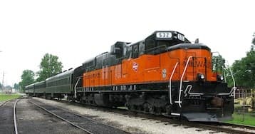 Classic orange train on tracks at rural station, scenic heritage excursion