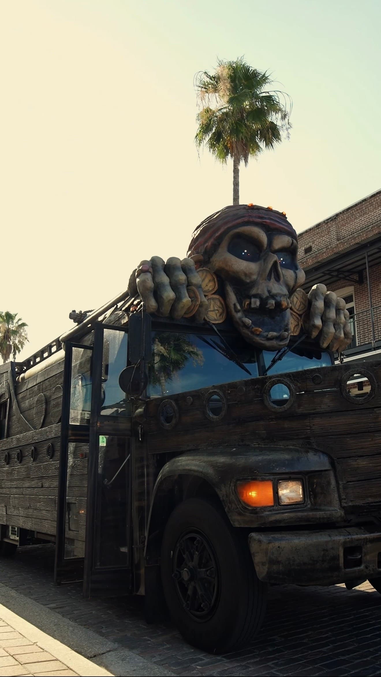 Decorated pirate skull bus cruising along palm-lined Tampa street