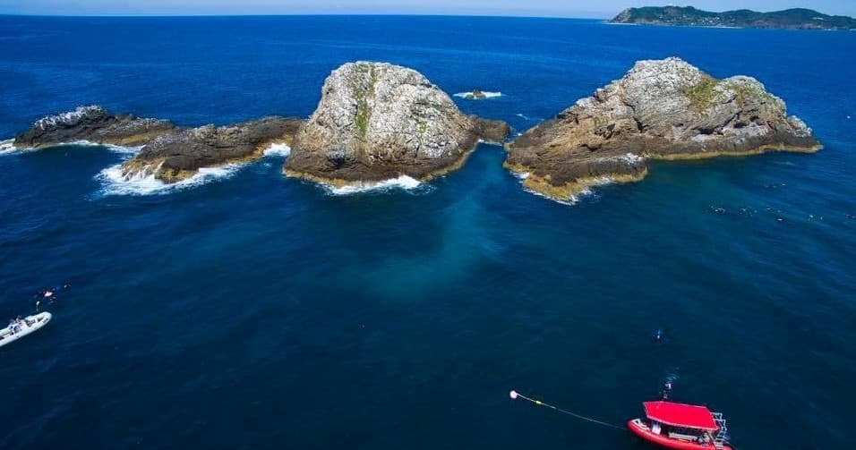 Aerial view of rocky islands and boats along ocean coast