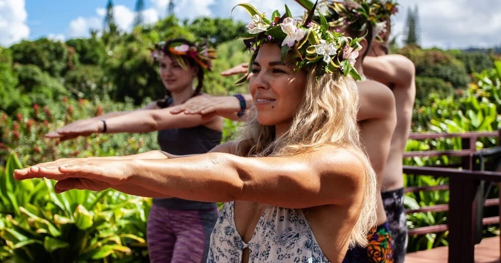Women practicing hula outdoors on lush tropical garden deck